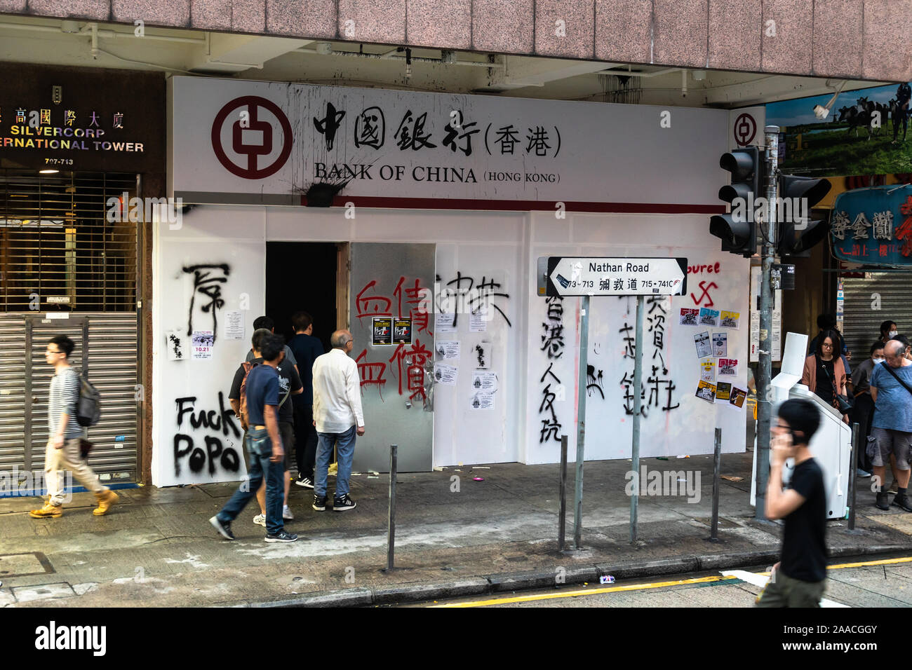 Kowloon, Hong Kong - 20 de octubre de 2019: la gente y los manifestantes caminar delante de una sucursal del Banco de China destrozado para protestar contra la ley de extradición una Foto de stock