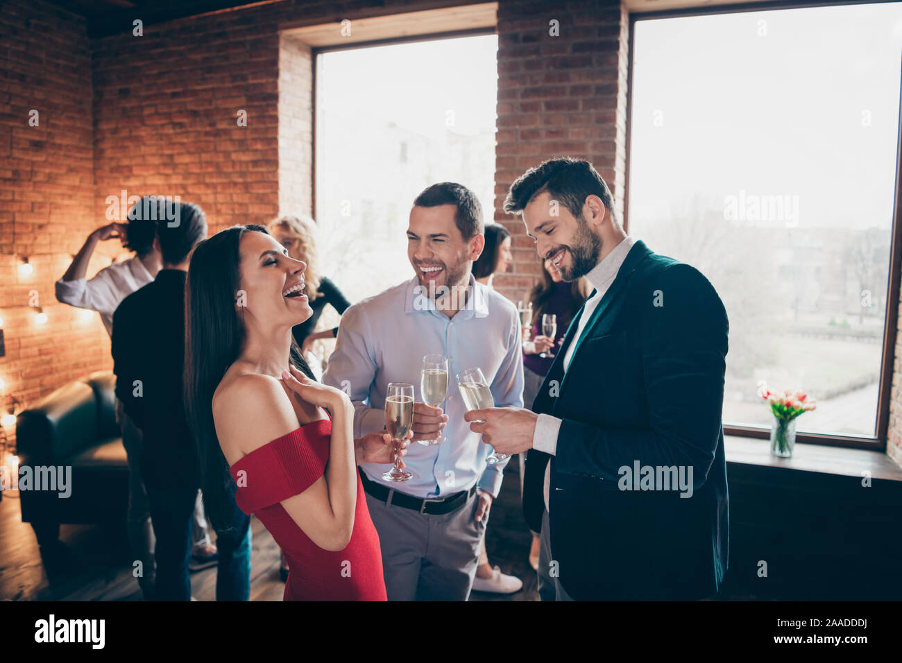Foto de positiva alegre bonita chica guapa riendo con otros hombres bromeaba en su celebración vasos de alcohol vistiendo formalmente Foto de stock