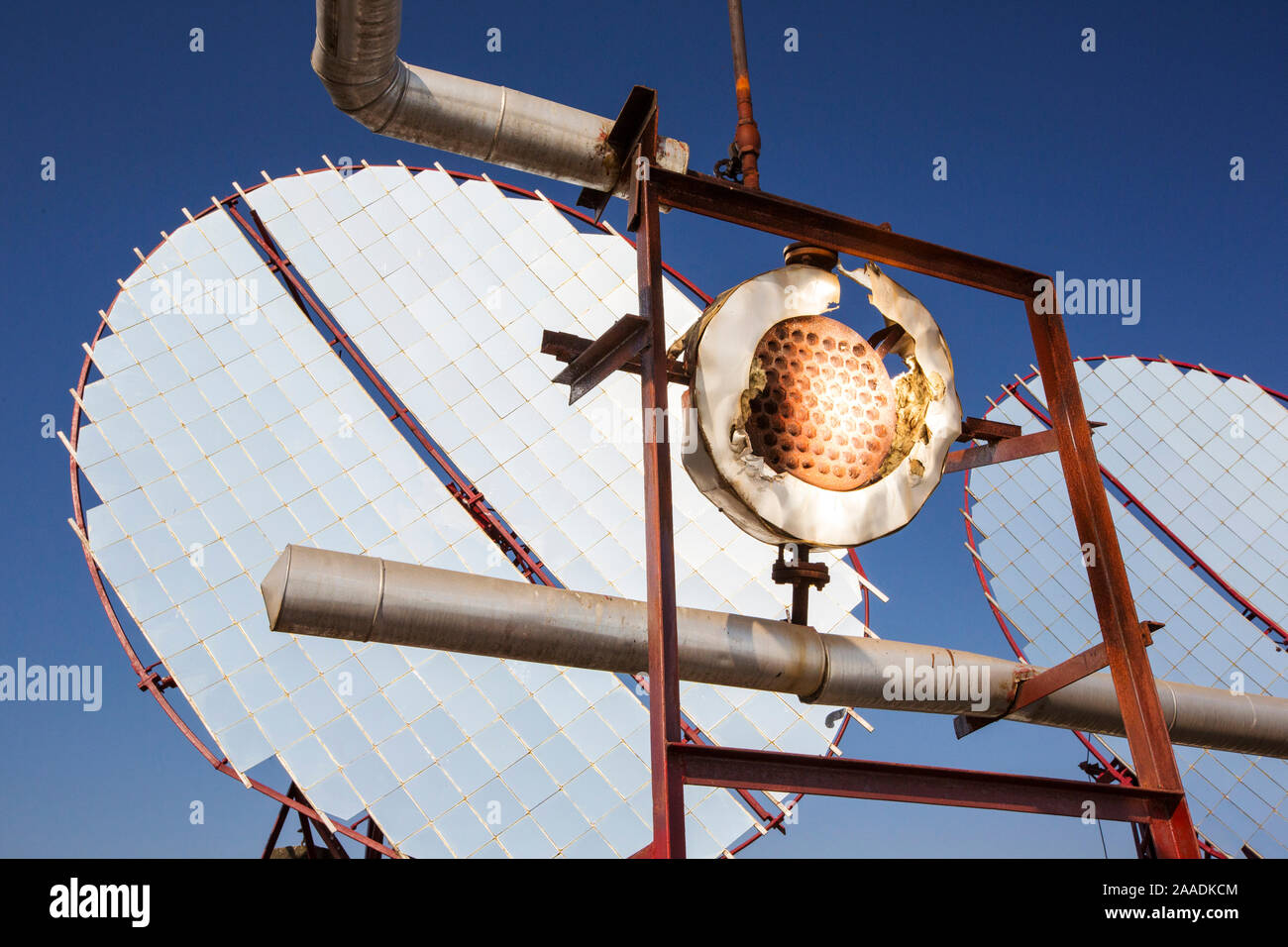 Los paneles solares que se enfocan los rayos del sol en los intercambiadores de calor para hervir el aceite, que luego es enviado a las cocinas de abajo para calentar las cocinas. Muni Seva Ashram, Goraj, cerca de Vadodara, India, diciembre de 2013. Foto de stock