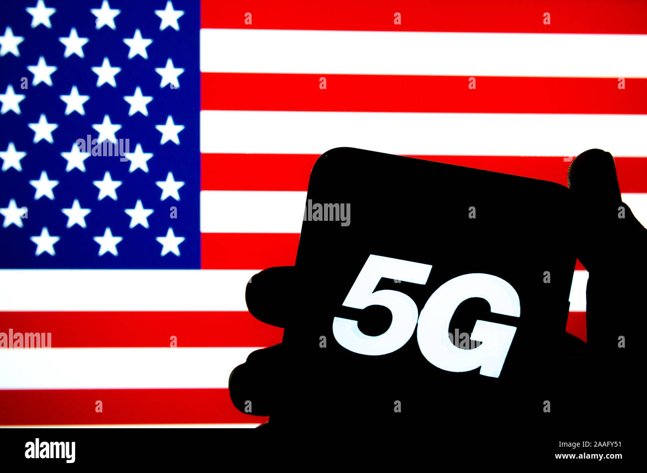 5G cartas con una silueta de un smartphone mantenga a mano con la bandera de los Estados Unidos sobre un fondo difuminado pantalla. Foto auténtica,no una montaña Foto de stock