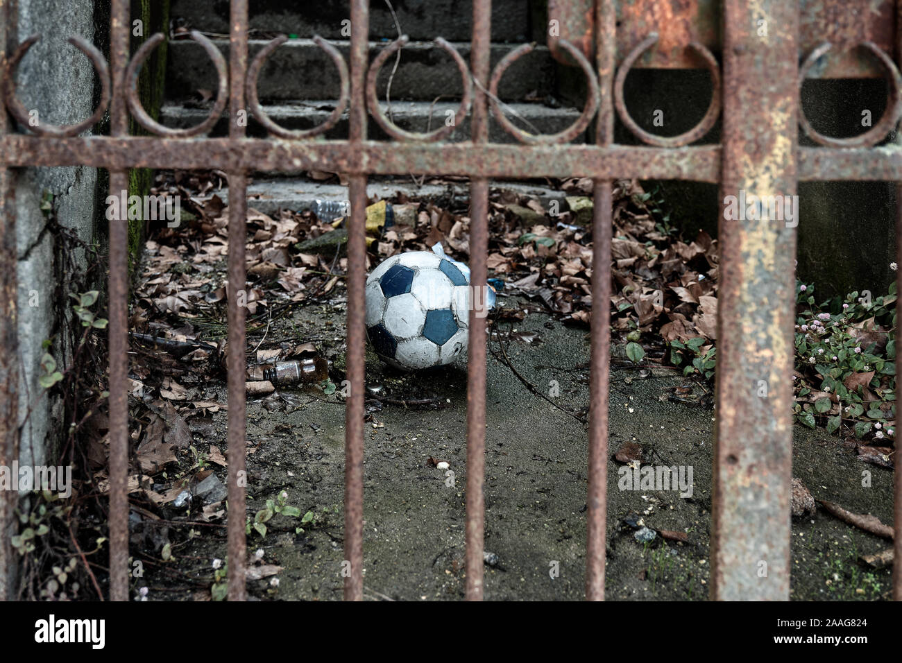 El balón de fútbol está cercada, detrás de las rejas de un portón de hierro oxidado. Foto de stock