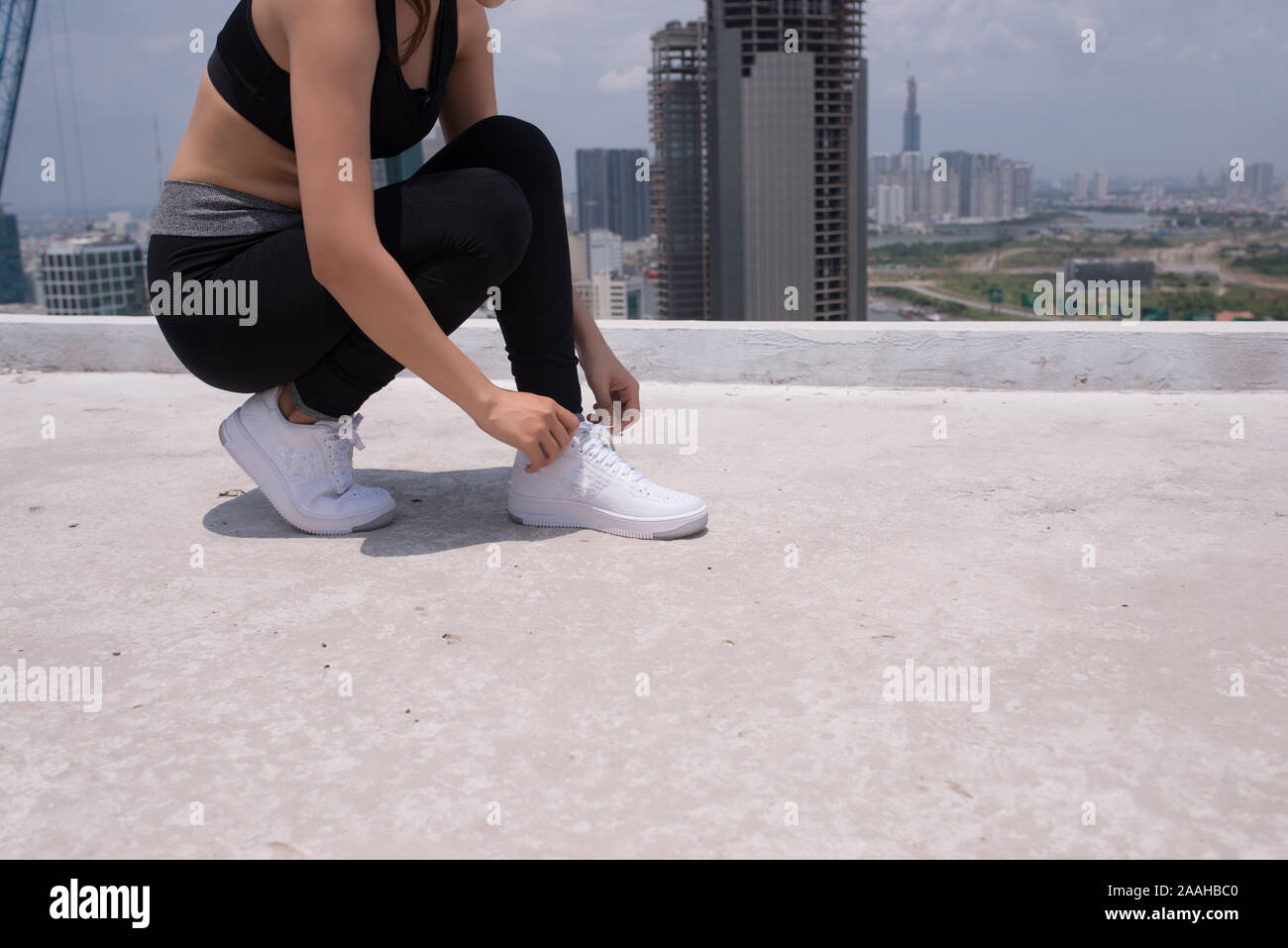 Cerca de pies chica deportiva en cuclillas. Ella es atarse los cordones  después del verano la actividad deportiva Fotografía de stock - Alamy