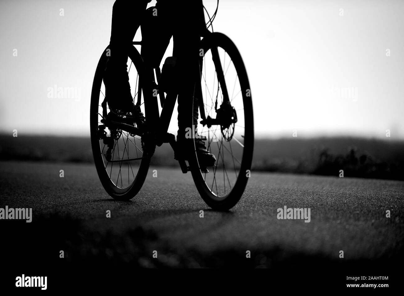 Fotografía en blanco y negro de la bicicleta de carretera y las piernas de un hombre irreconocible. Muy poca profundidad de campo. Foto de stock