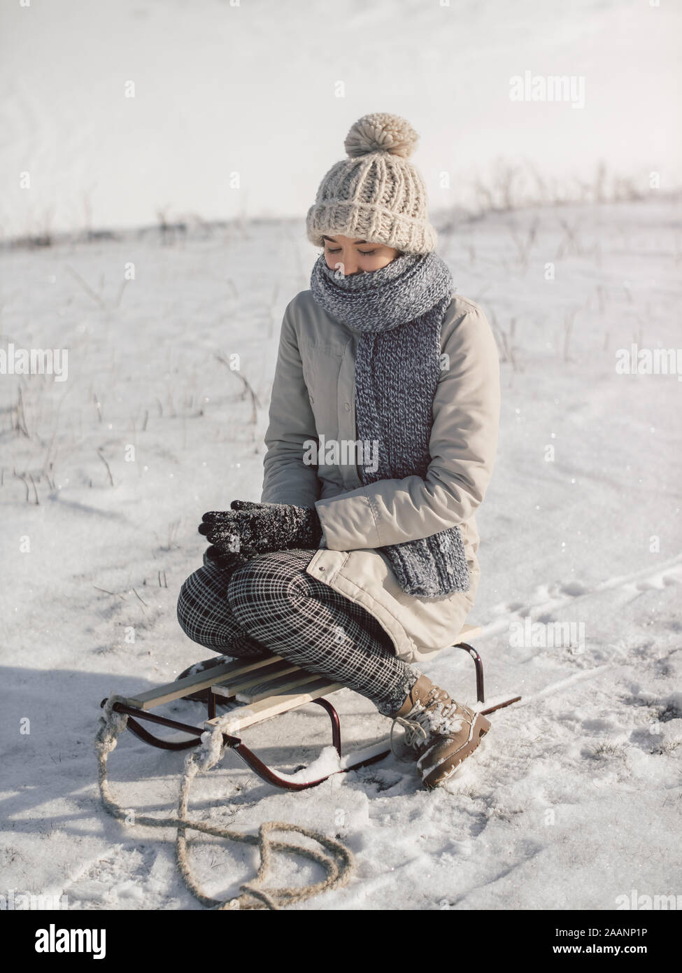 Mujer joven con sled vestida con ropa de invierno casual. Lindo gracioso  mestizos caucásicos mujer asiática sentado en el trineo retro cerca de  nieve cuesta abajo. Una mujer que padece en un