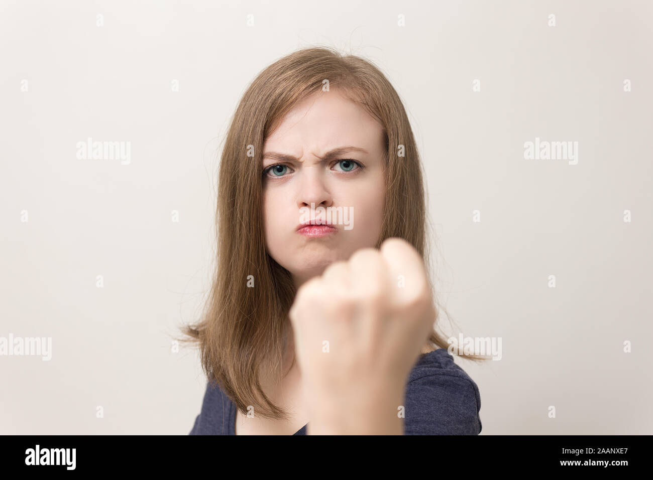 Mujer caucásica joven con una mirada claramente irritada, molesta, muestra puño Foto de stock