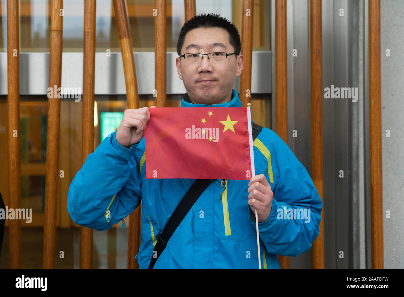 Edimburgo, Escocia, Reino Unido. 23 de noviembre de 2019. Concentración y Marcha en apoyo del movimiento Pro-Democracy en Hong Kong organizado por la Democracia de Hong Kong en Escocia grupo comenzó en la Catedral de St Giles y procedió a lo largo de la Royal Mile en el Parlamento Escocés. Se intentó entregar una carta pidiendo el gobierno escocés para apoyar el movimiento Pro-Democracy en Hong Kong pero no MSP (Miembro del Parlamento Escocés ) a disposición de recibirla. Foto; un solitario manifestante Pro-Beijing al Parlamento escocés. Iain Masterton/Alamy Live News. Foto de stock