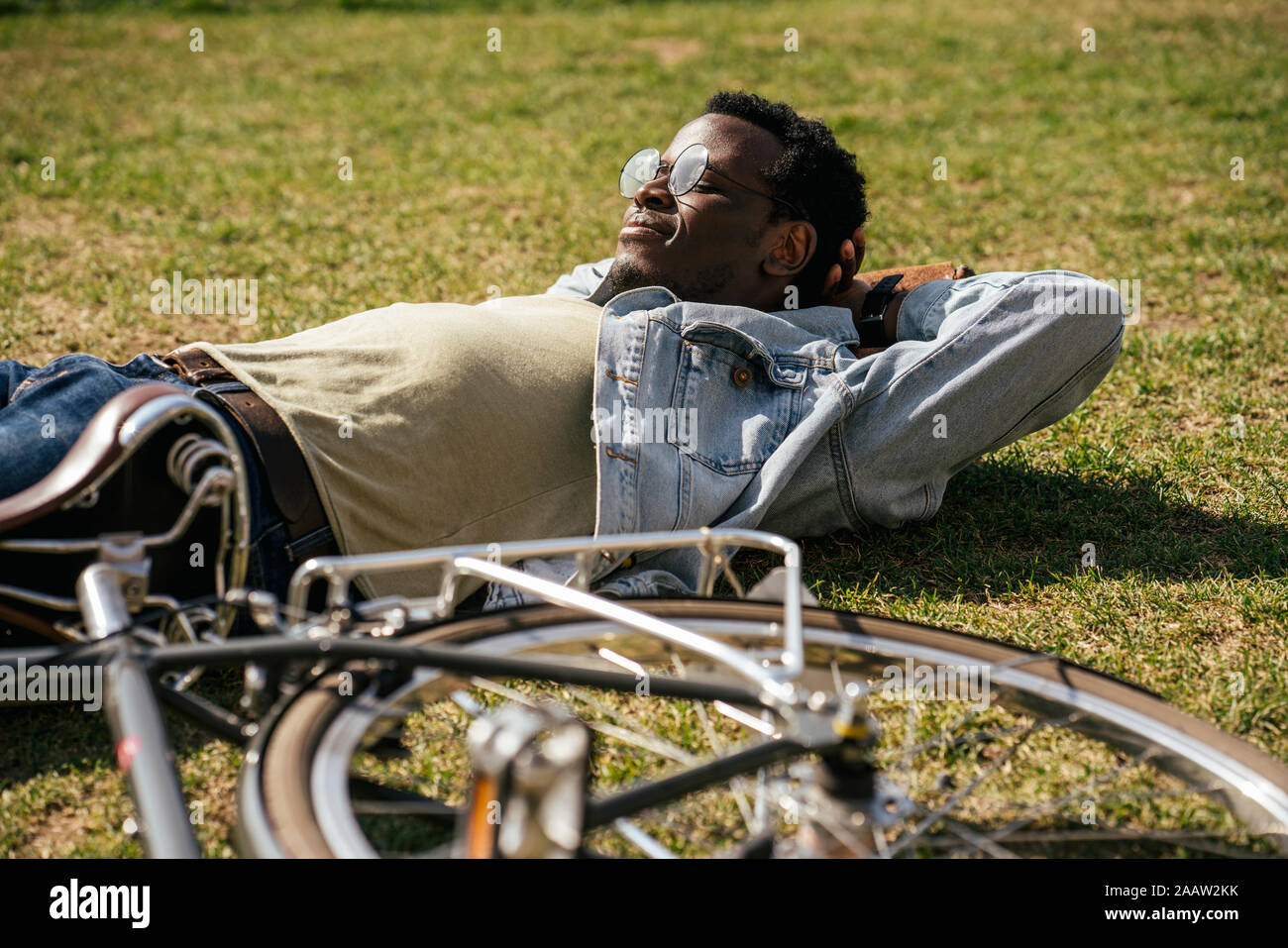 Joven con bicicleta, relajante, tumbado sobre el césped Foto de stock