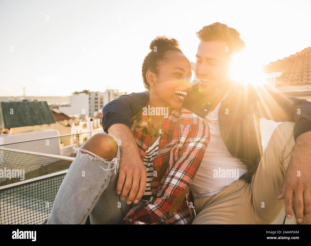 Afectuoso feliz pareja joven sentado en la azotea al atardecer Foto de stock