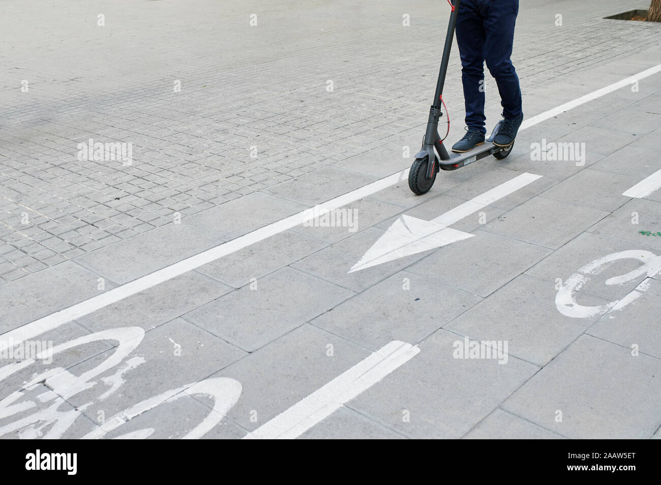 Las piernas del hombre caballo e-scooter de carril bici en la ciudad Foto de stock