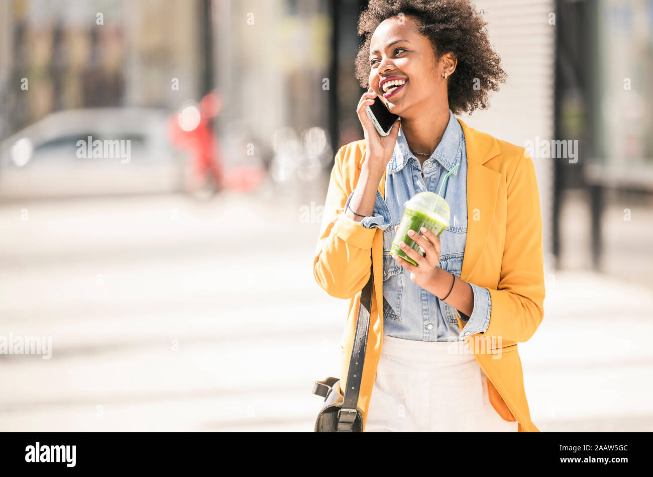 Mujer joven feliz en el teléfono en la ciudad Foto de stock