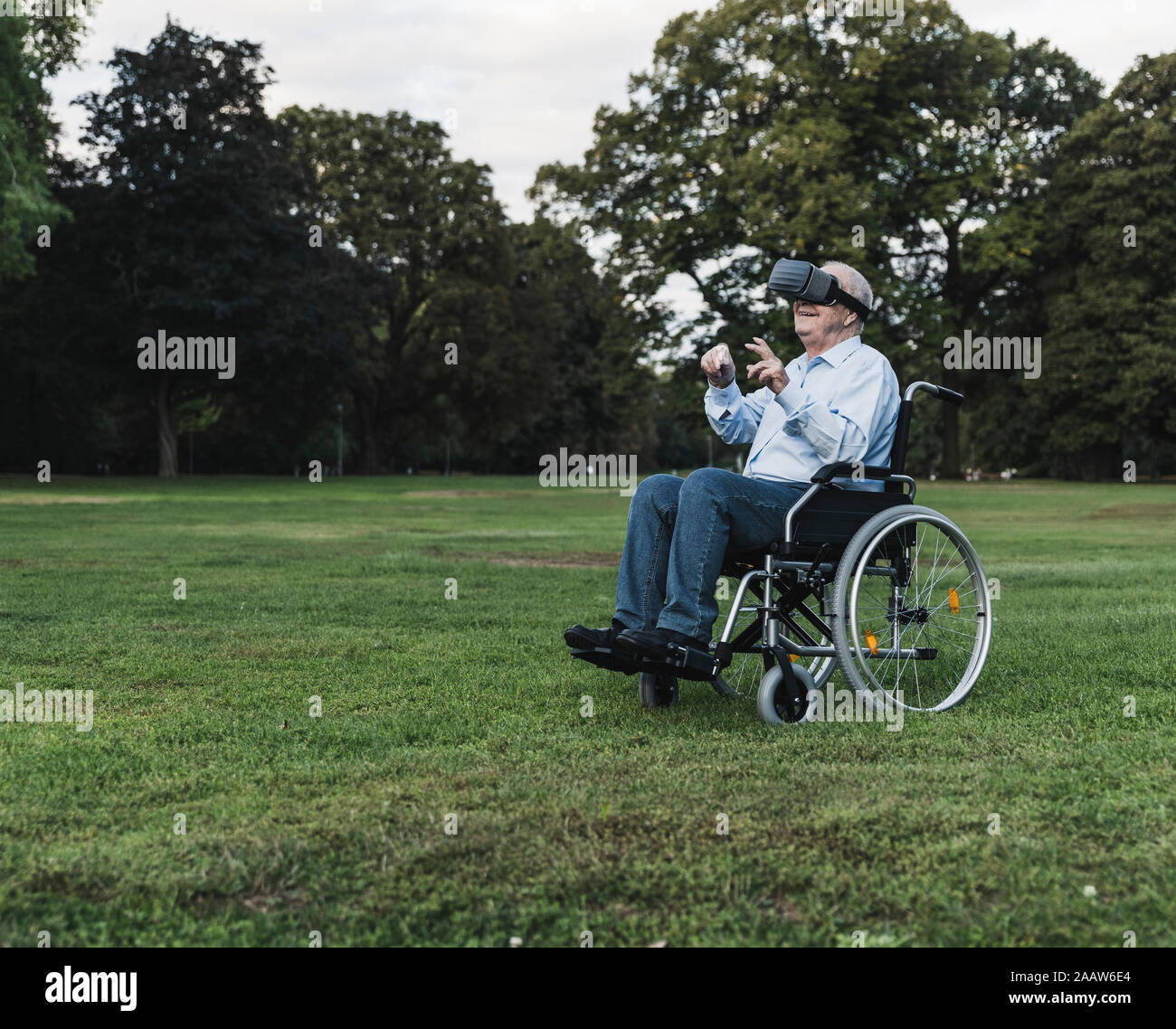 Altos hombre sentado en la silla de ruedas en un parque utilizando gafas de realidad virtual Foto de stock