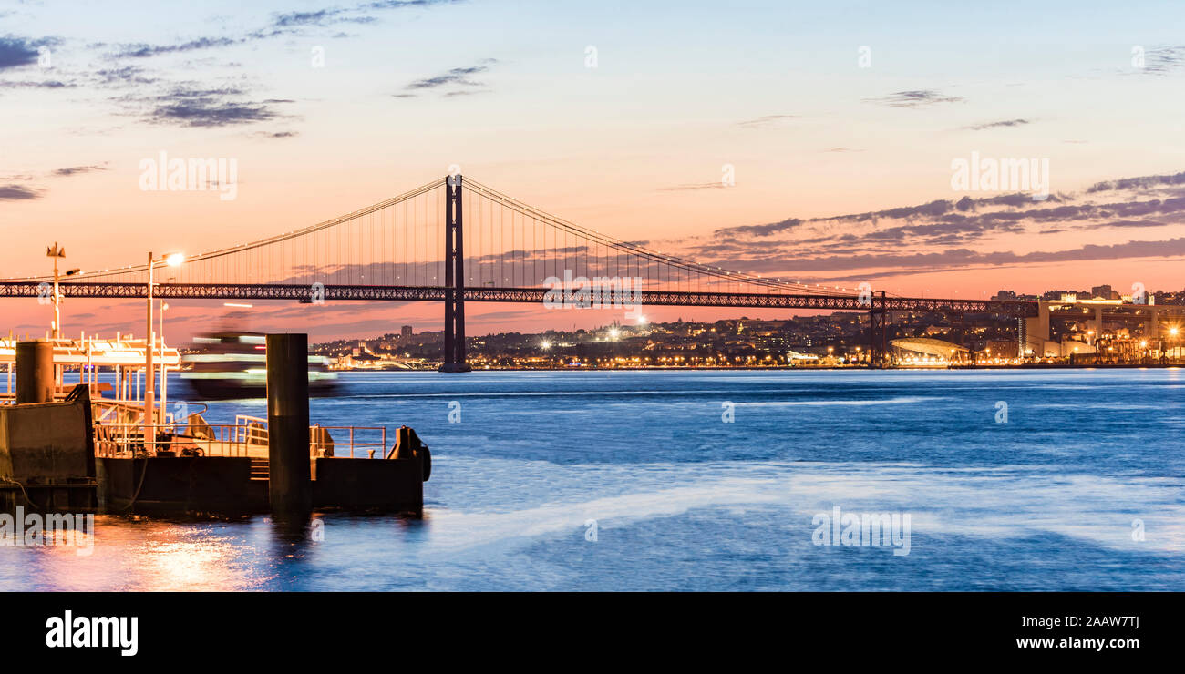 El 25 de abril de puente sobre el río Tajo visto desde Cacilhas al atardecer, Lisboa, Portugal Foto de stock