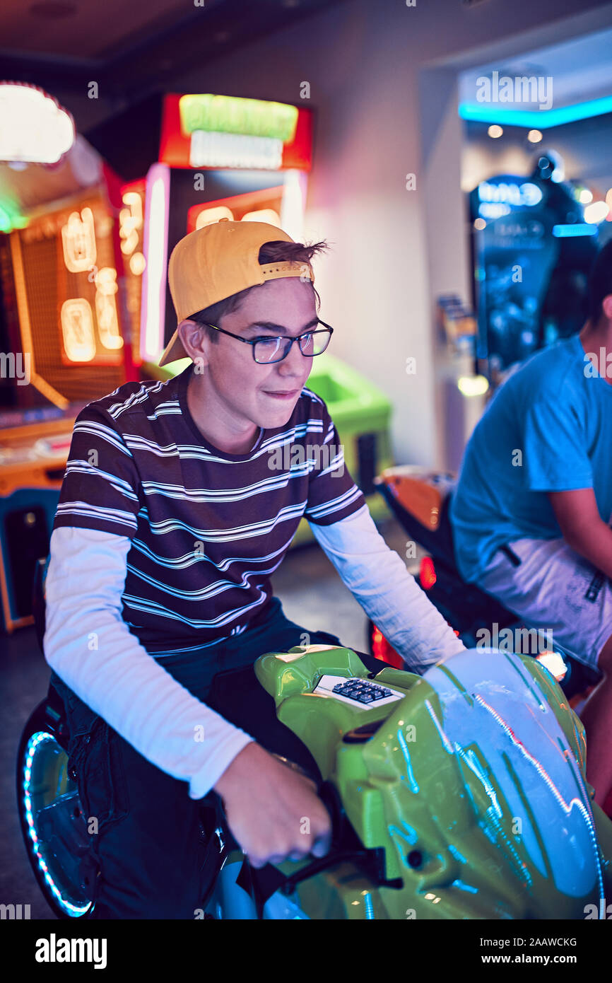 Adolescente jugando con un simulador de conducción en una diversión arcade Foto de stock
