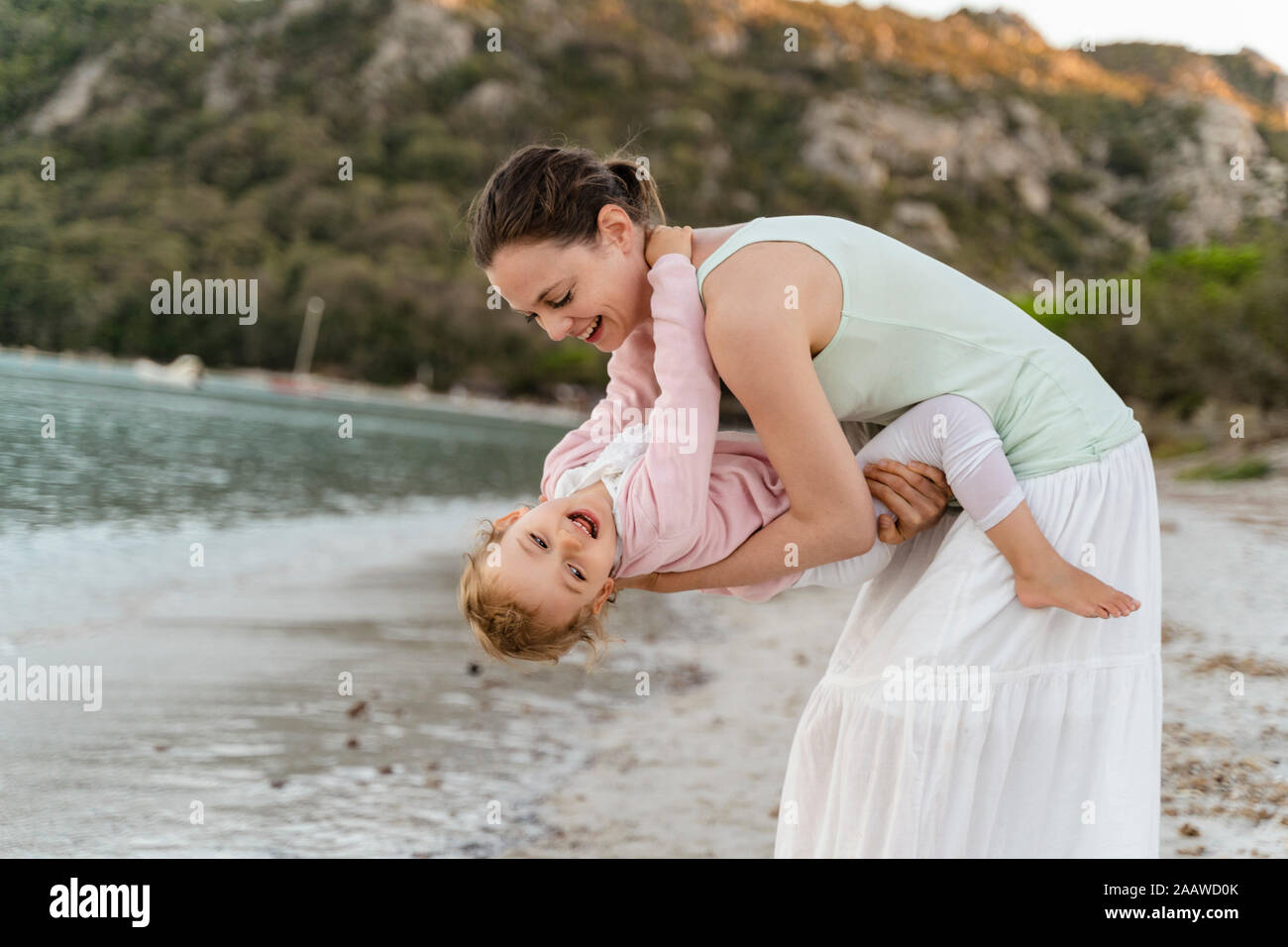 Feliz madre llevar a su hija en la playa Foto de stock