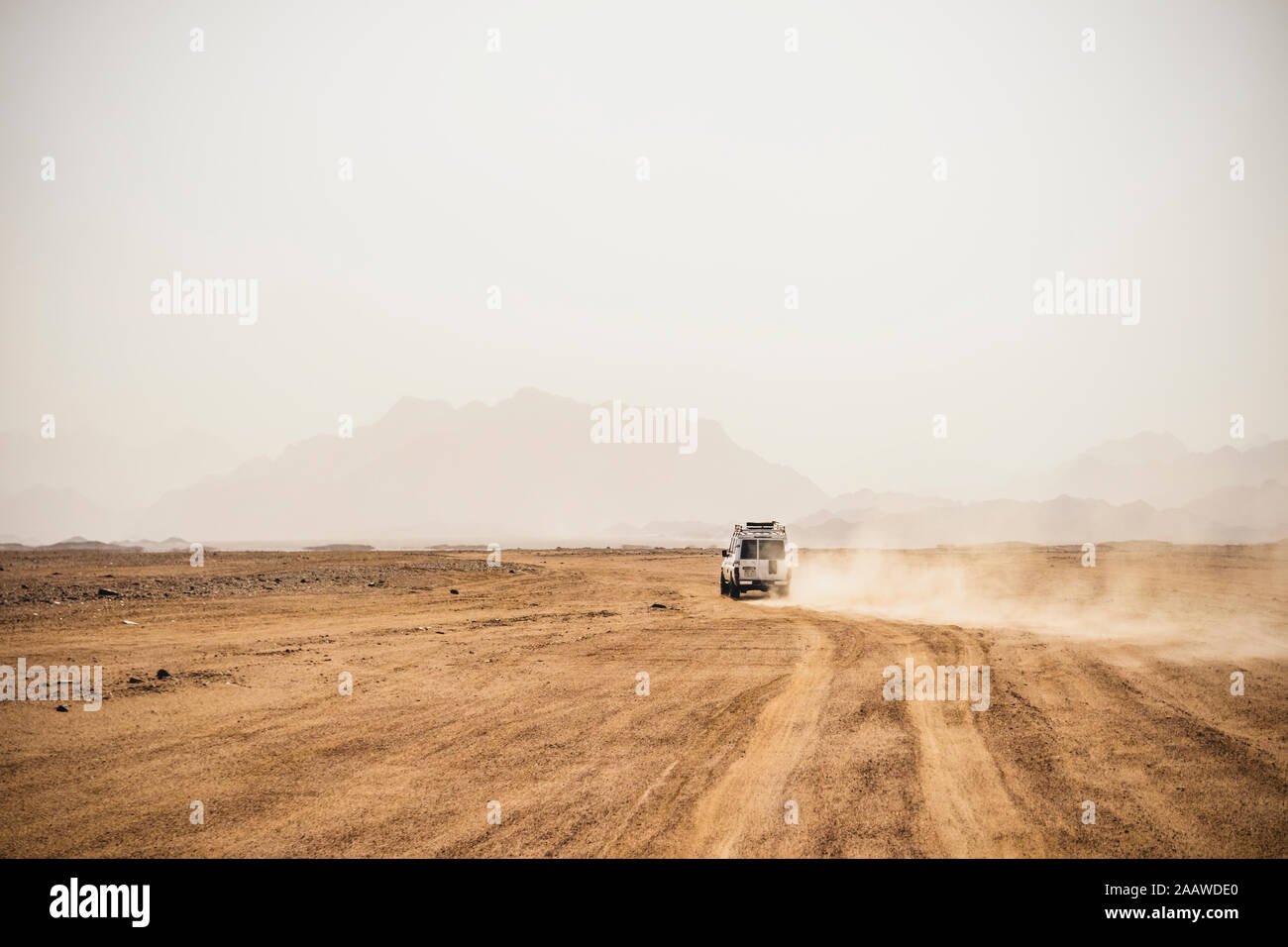 Vehículo off-road moviendo el árido paisaje contra el cielo despejado durante el día soleado, Suez, Egipto Foto de stock