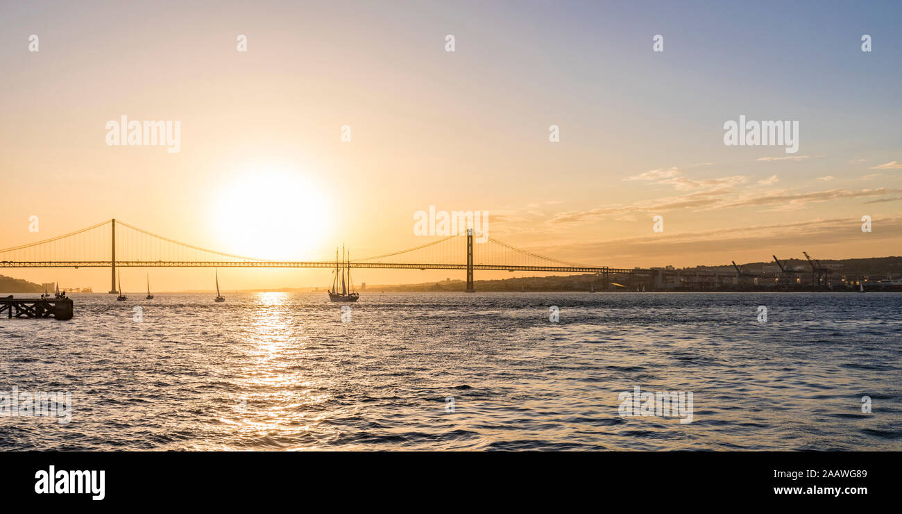 El 25 de abril de puente sobre el río Tajo contra el cielo durante el atardecer en Lisboa, Portugal. Foto de stock