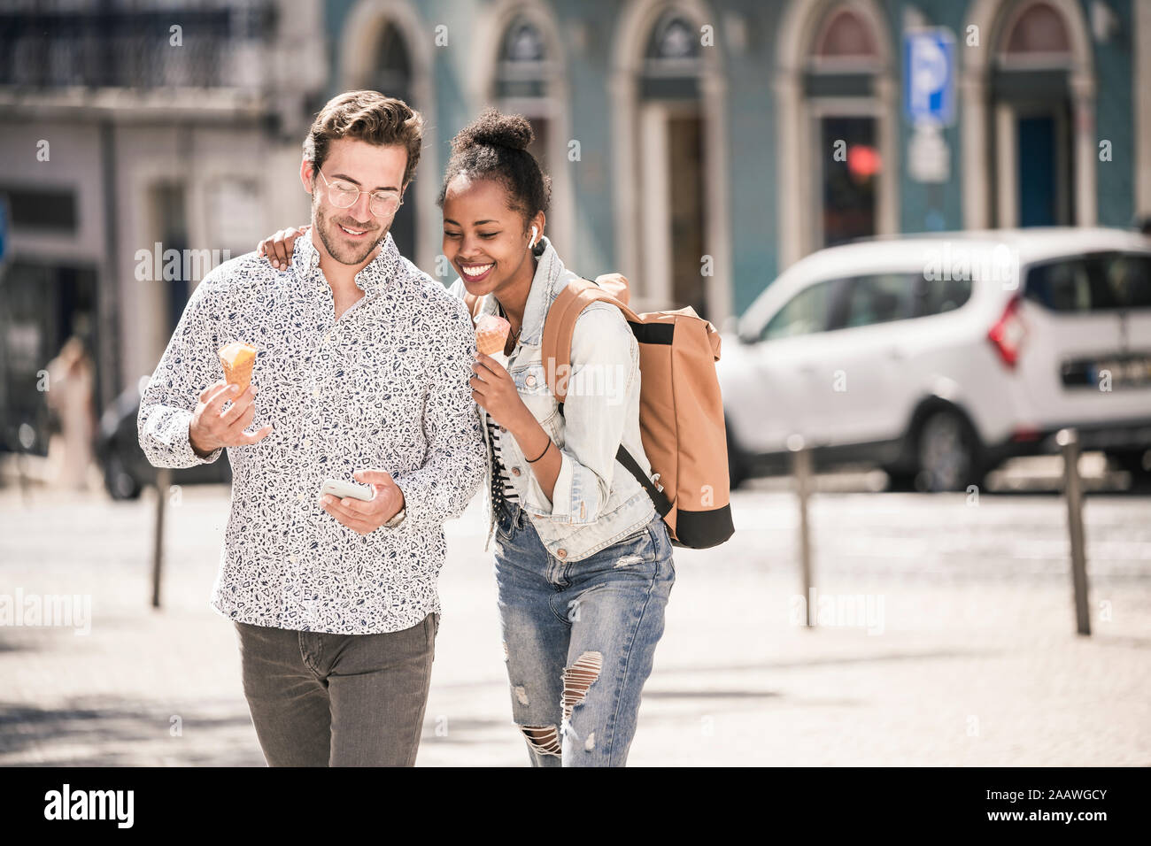 Feliz pareja joven con helado y el teléfono móvil en la ciudad, Lisboa, Portugal Foto de stock