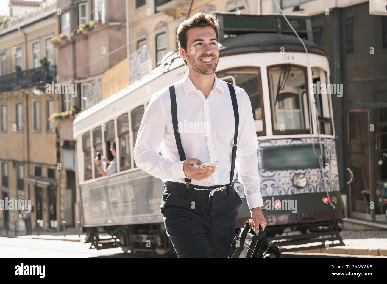 Sonriente joven empresario en el casco antiguo de la ciudad, sobre la marcha, Lisboa, Portugal Foto de stock