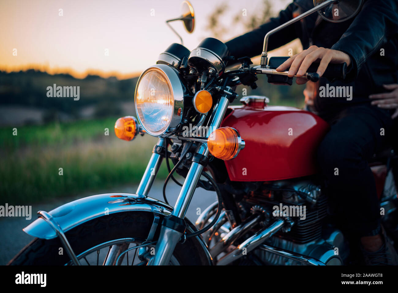 Disparo de cosecha de la pareja en vintage moto al atardecer Foto de stock