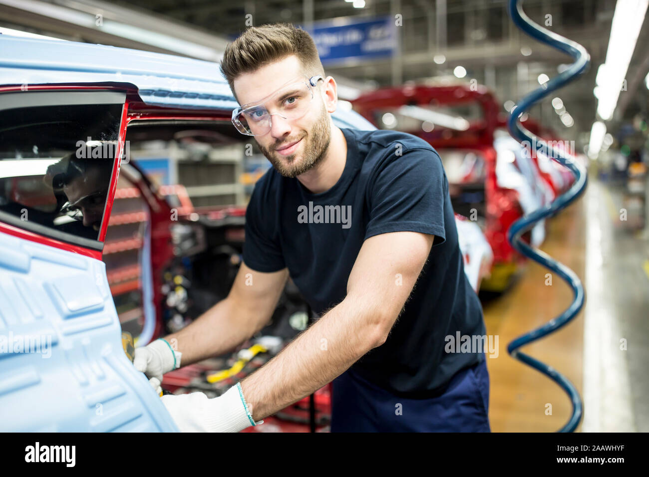 Retrato del hombre que confía en el trabajo en la fábrica de coches modernos Foto de stock