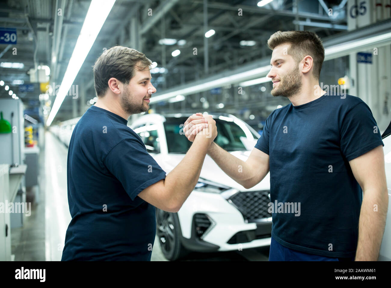 Dos colegas, un apretón de manos en la moderna fábrica de coches Foto de stock