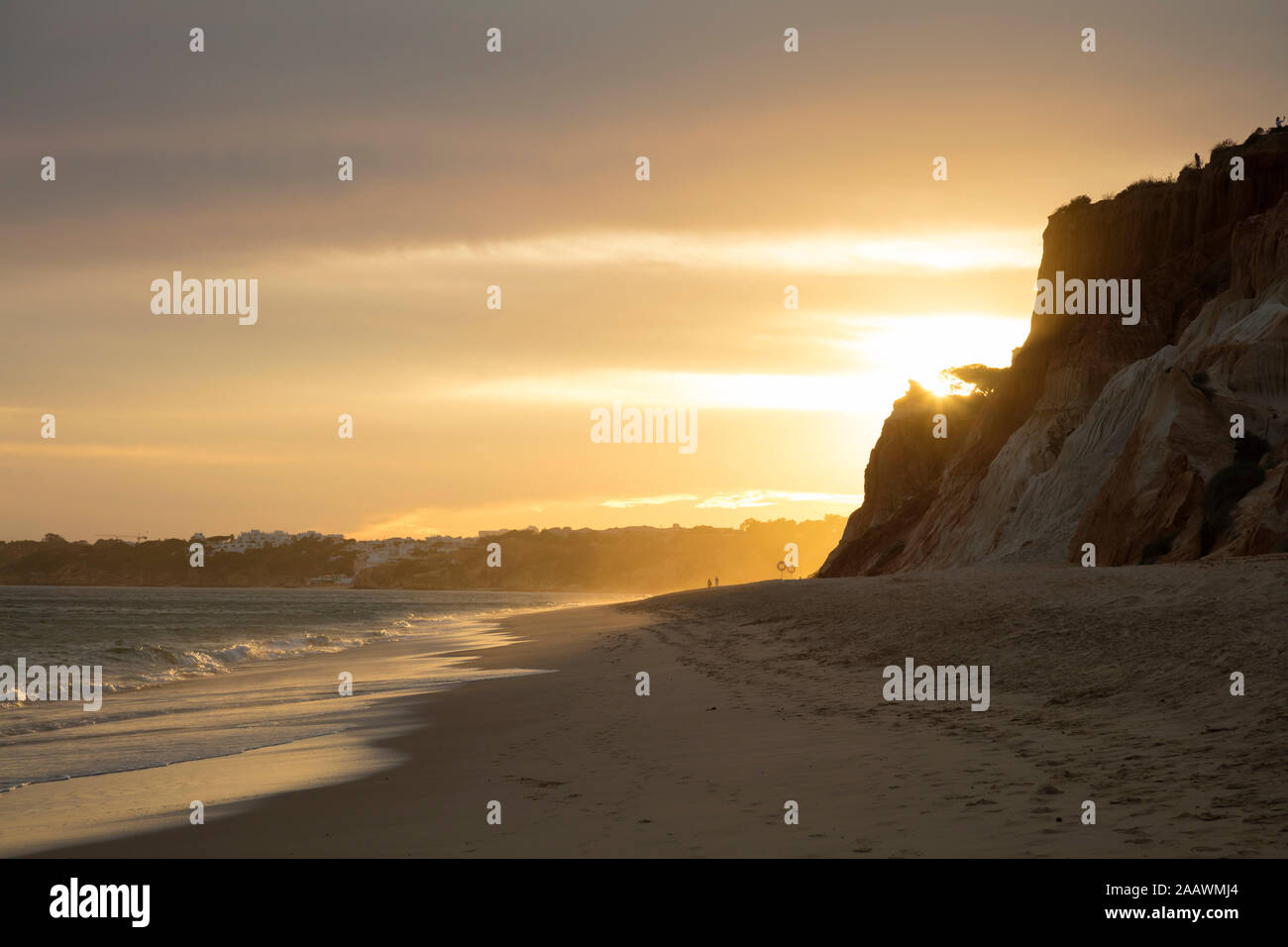 Vista panorámica de la playa contra el cielo nublado durante la puesta de sol, costa Atlántica, Algarve, Portugal Foto de stock