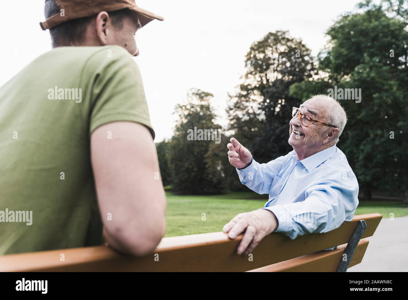 Feliz el hombre senior relajante junto con su nieto en una banca del parque Foto de stock