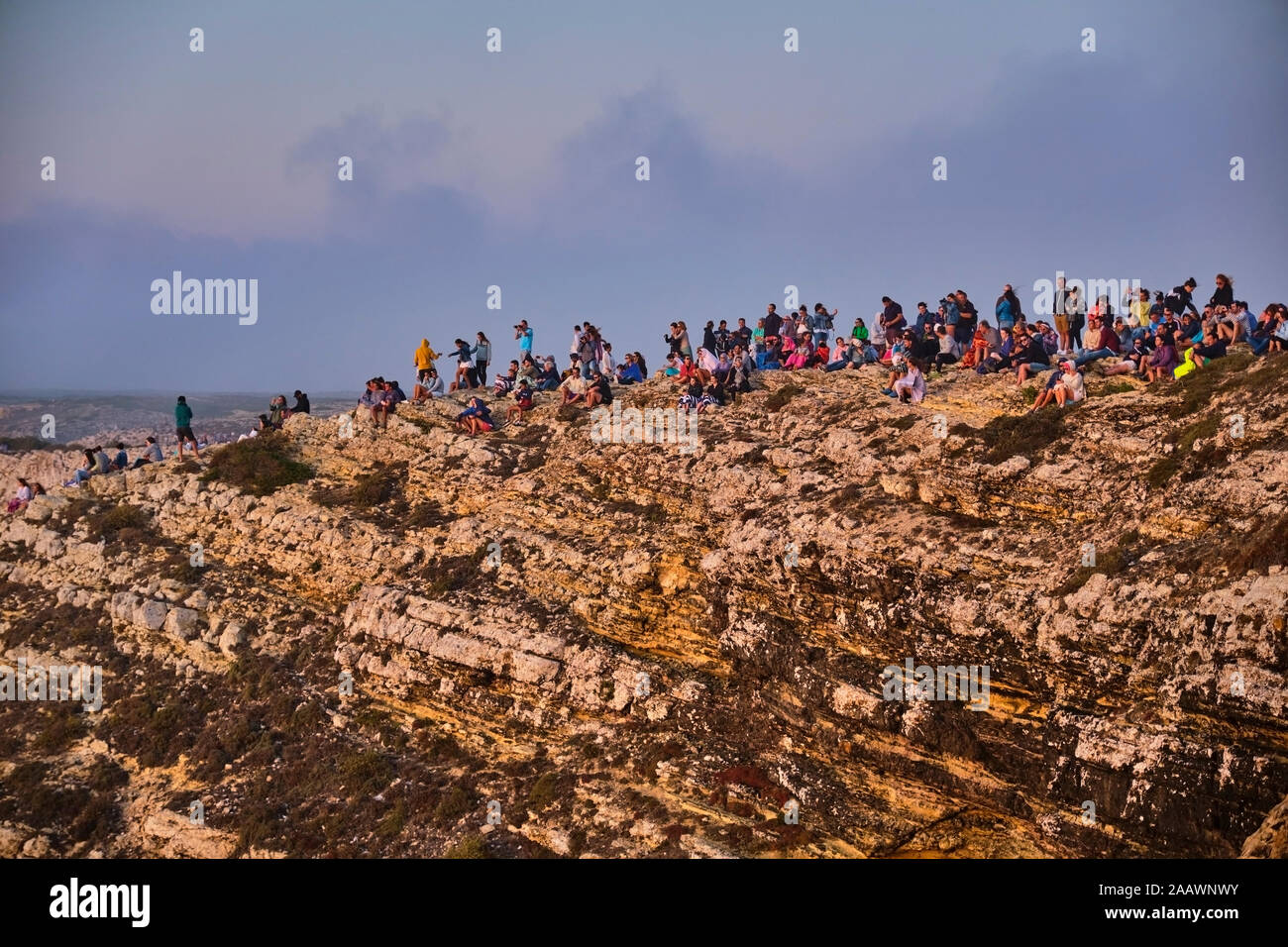 Portugal, Algarve, un gran grupo de personas admirando el mar desde el borde del acantilado en el Cabo de San Vicente Foto de stock