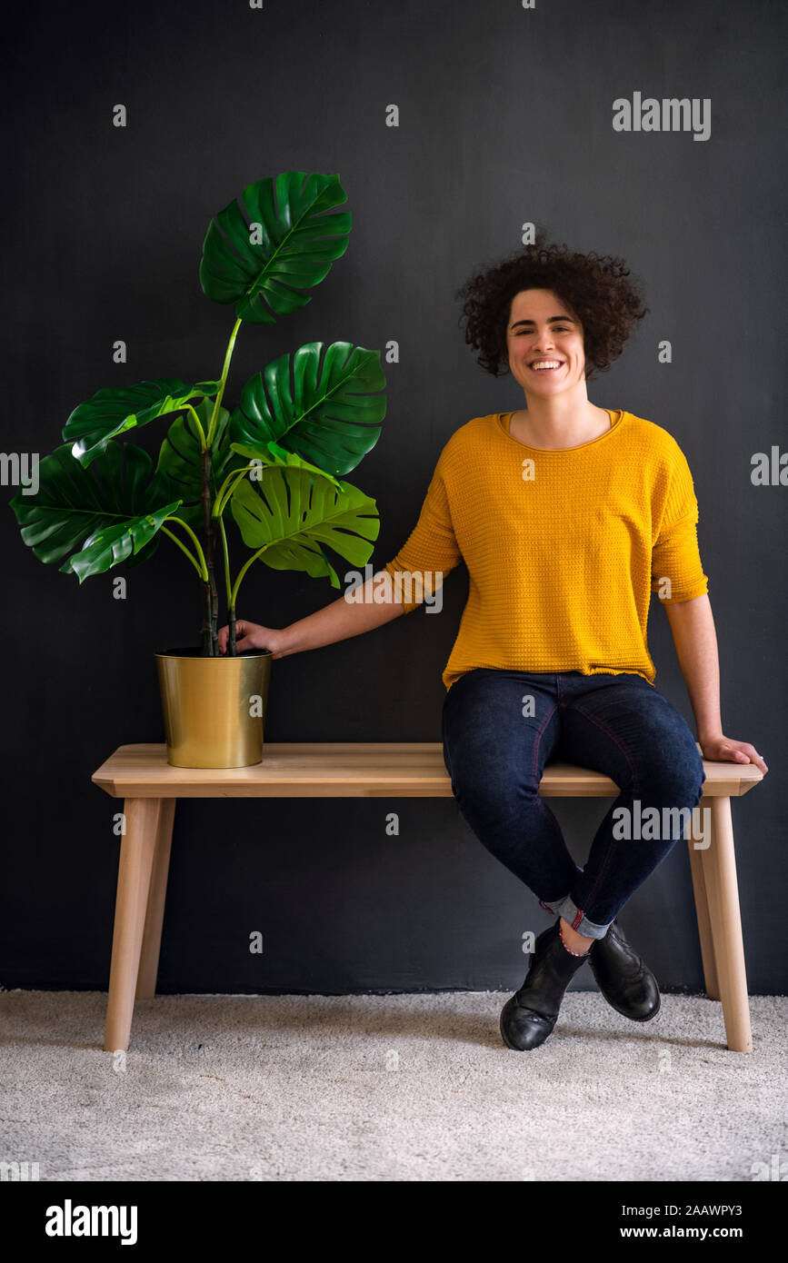 Retrato de mujer joven sosteniendo una planta de casa y mirando a la cámara Foto de stock
