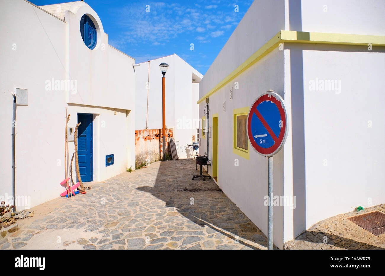 Portugal, Algarve, Arrifana, señales de carretera delante de adoquines vacía callejón entre casas blancas Foto de stock