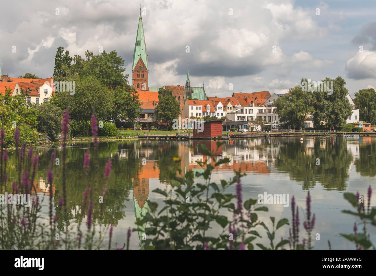 Casas y St. Aegidien-Kirche por Krähenteich lago contra el cielo nublado en Lübeck, Alemania Foto de stock