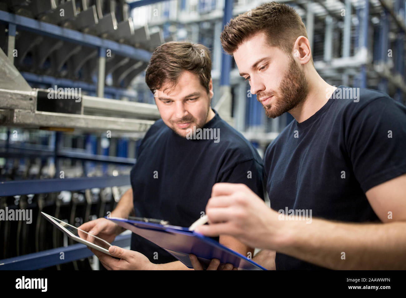 Dos trabajadores con el portapapeles y tablet en fábrica Foto de stock