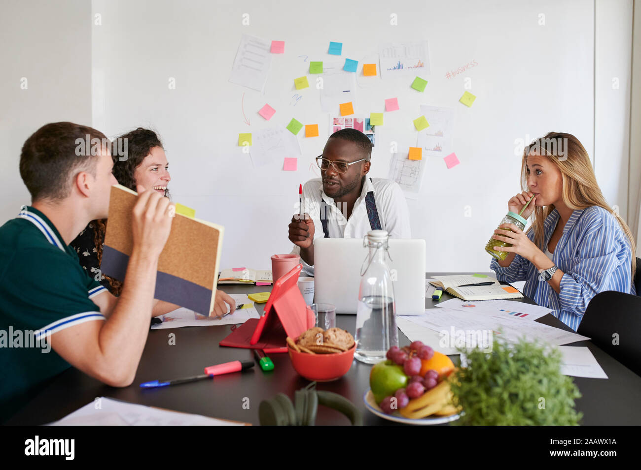Jóvenes empresarios brainstorming juntos alrededor de una mesa en una oficina. Foto de stock
