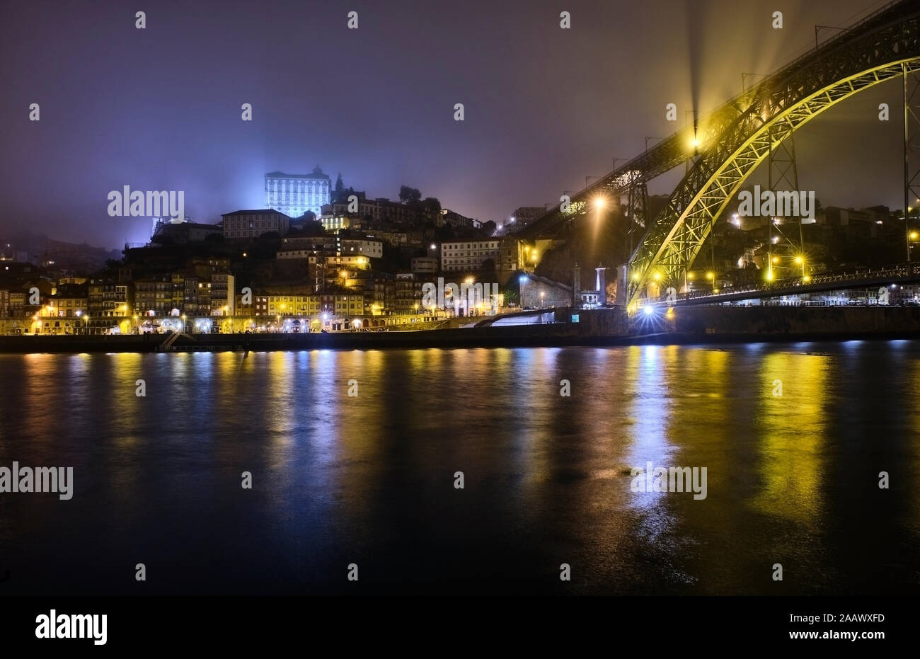 Portugal, Porto, Douro, ciudad iluminada y el puente Dom Luis visto sobre el agua Foto de stock