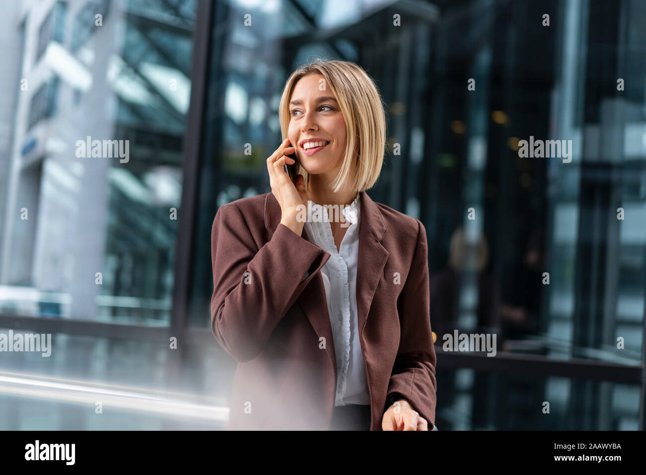 Sonriente joven empresaria en el teléfono en la ciudad Foto de stock
