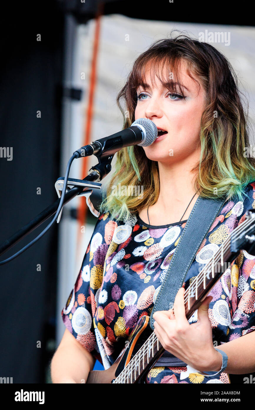 El cantautor francés, Estelle Mey actuarán en el Festival de salto Faversham. Mujer joven tocando la guitarra eléctrica y cantar en el micrófono. Foto de stock