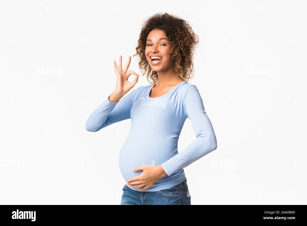 Emocionada afro embarazada mostrando gestos OK Foto de stock