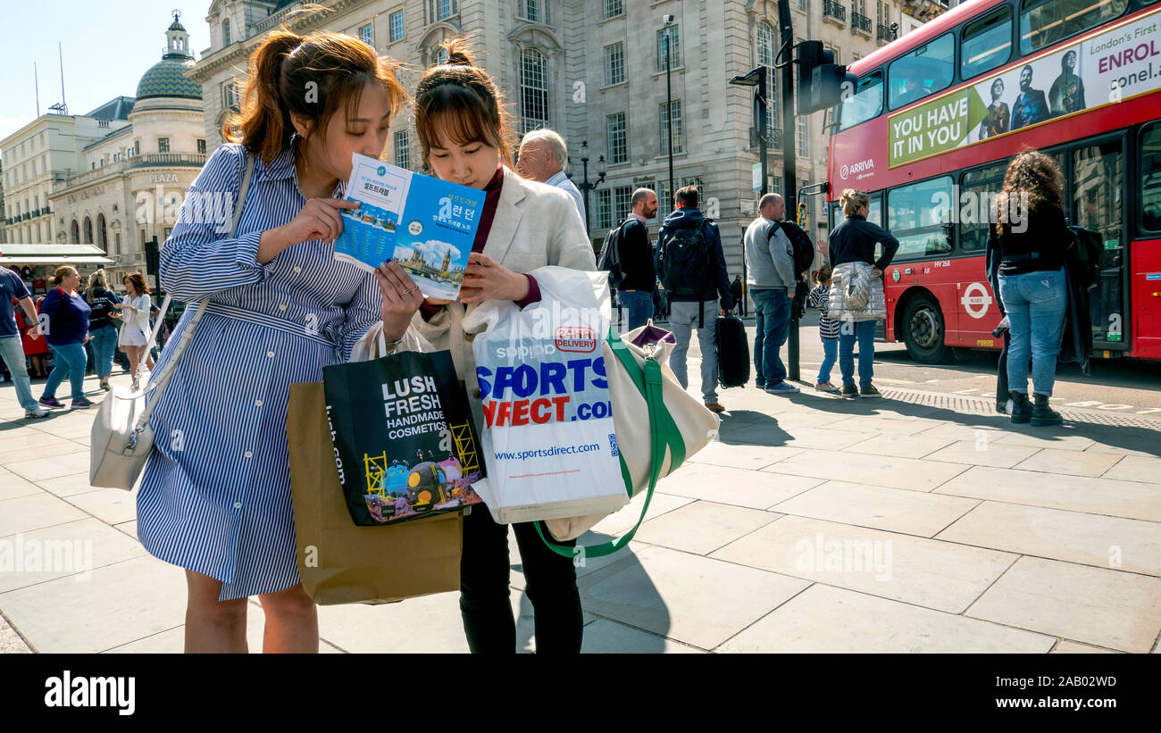 Las mujeres jóvenes consultar guía de viajes Piccadilly Londres Inglaterra Foto de stock