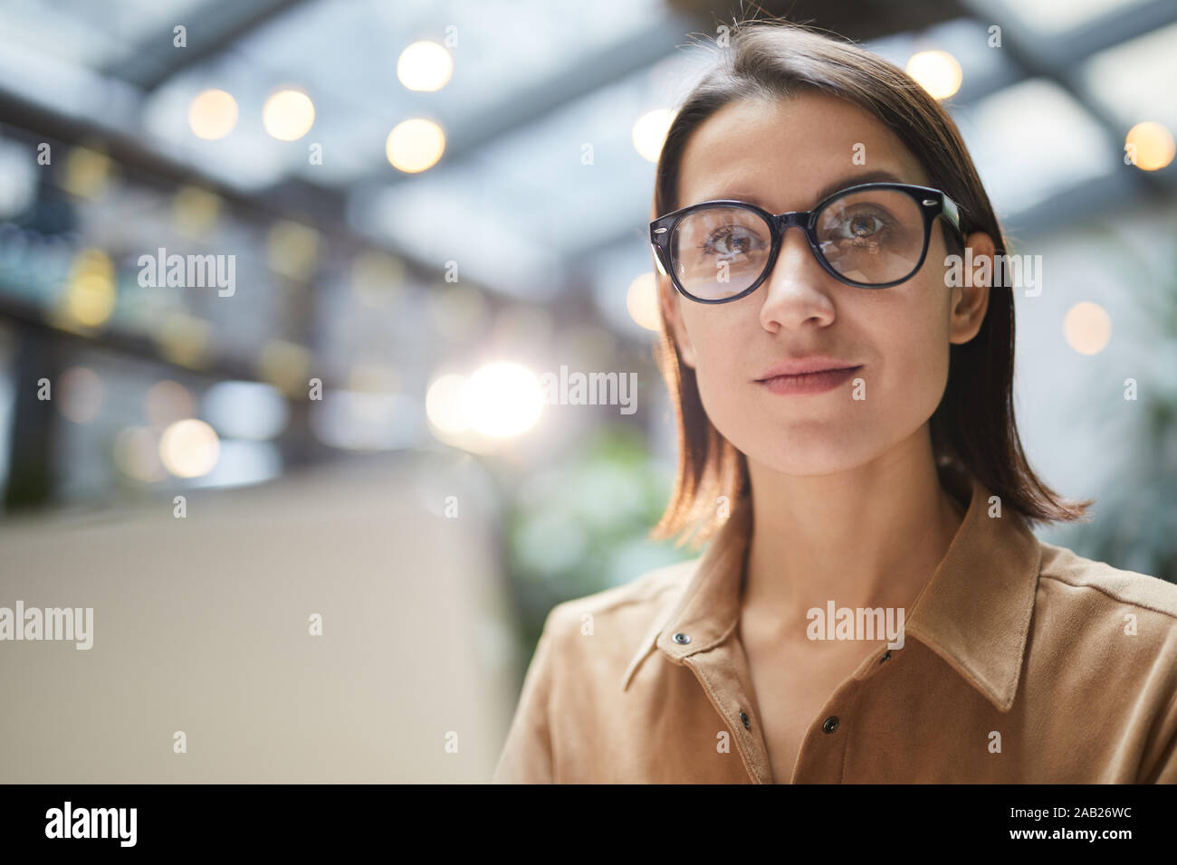 Retrato de la empresaria contemporánea lleva gafas, sonriendo a la cámara mientras se trabaja en la cafetería al aire libre, espacio de copia Foto de stock