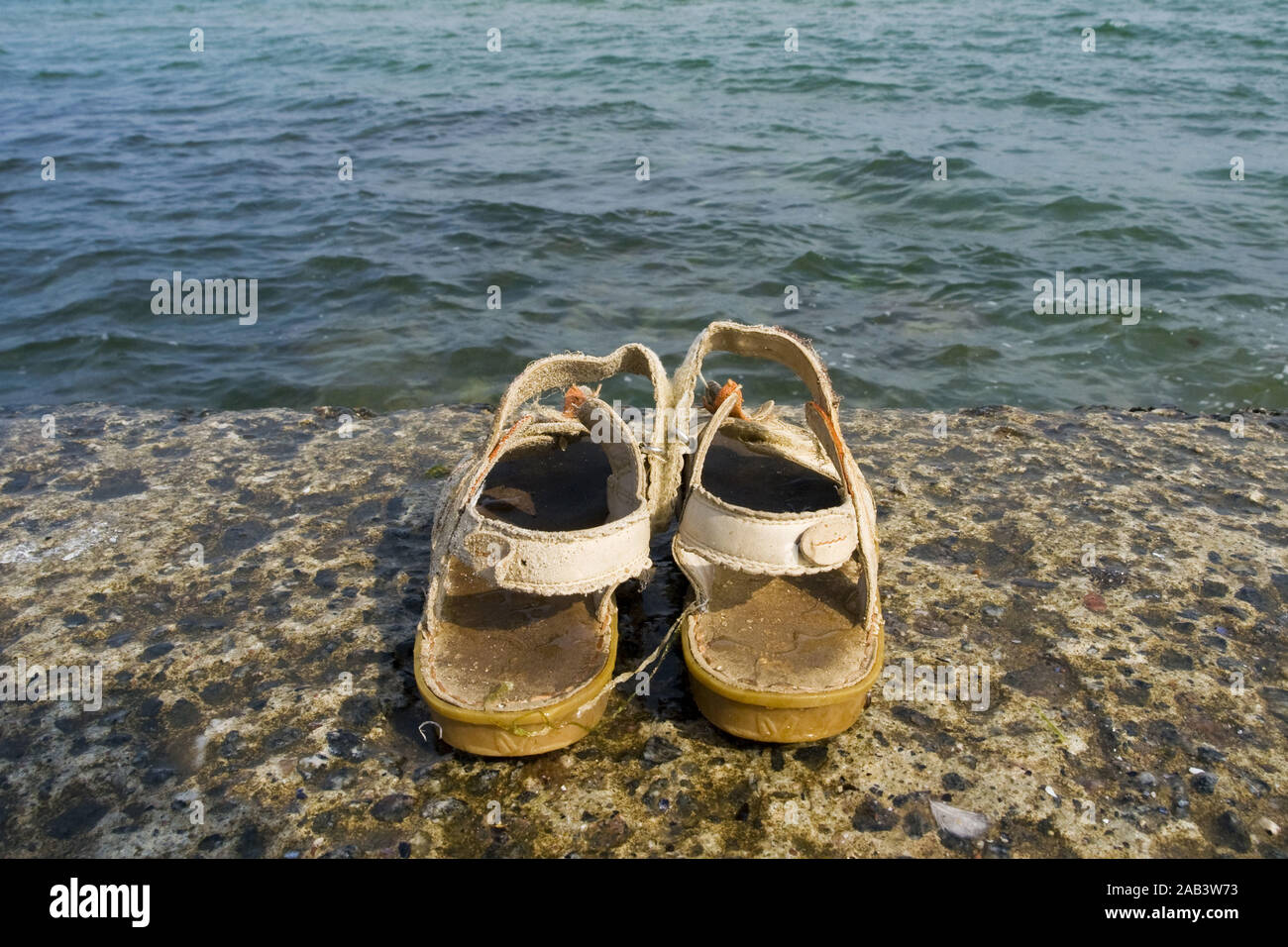 Sandalen auf einer Mauer am Wasser Foto de stock