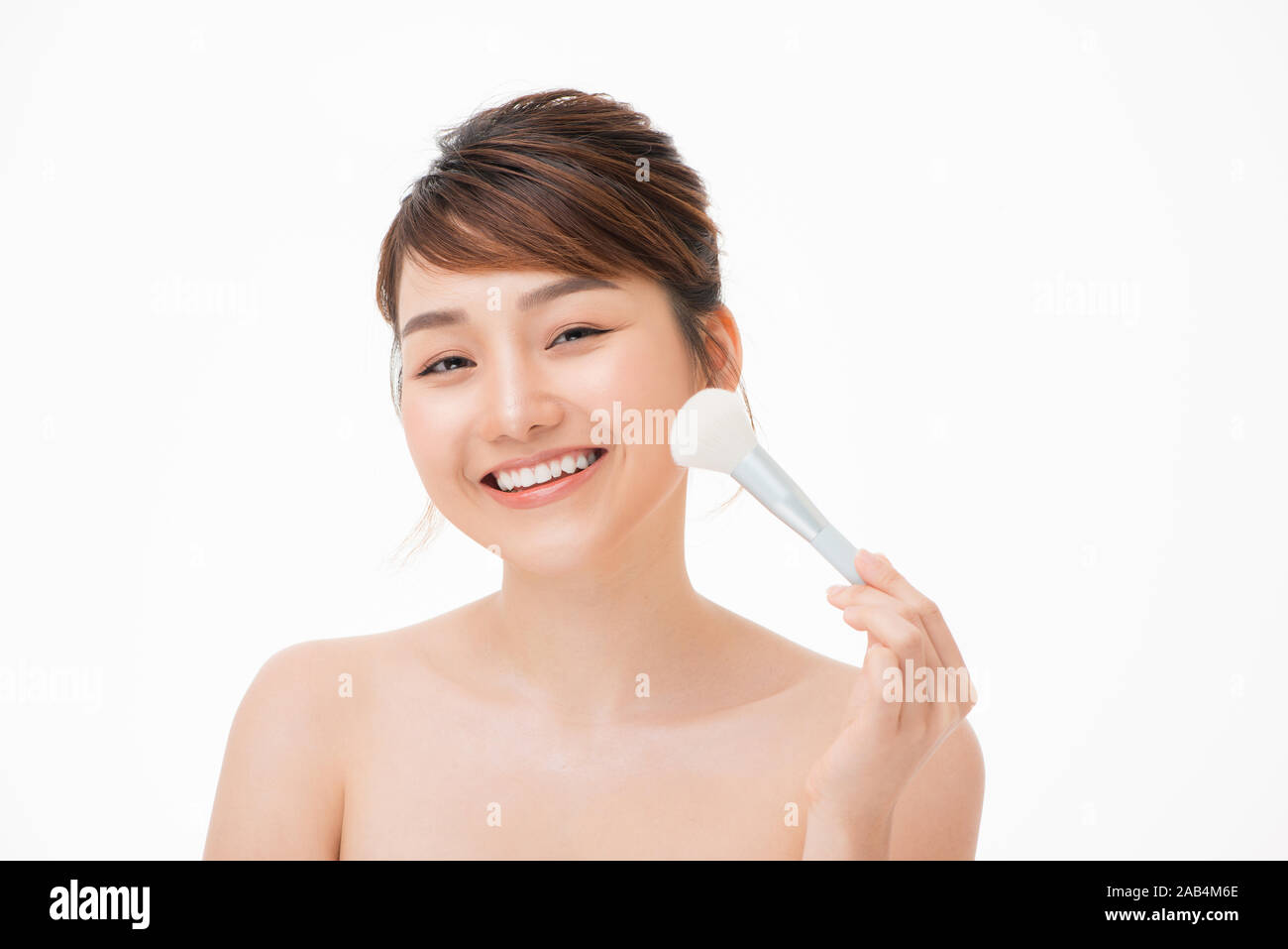 Retrato de belleza joven mujer asiática sonrisa con cepillos cosméticos y para el cuidado de la piel de las mejillas concepto. Foto de stock