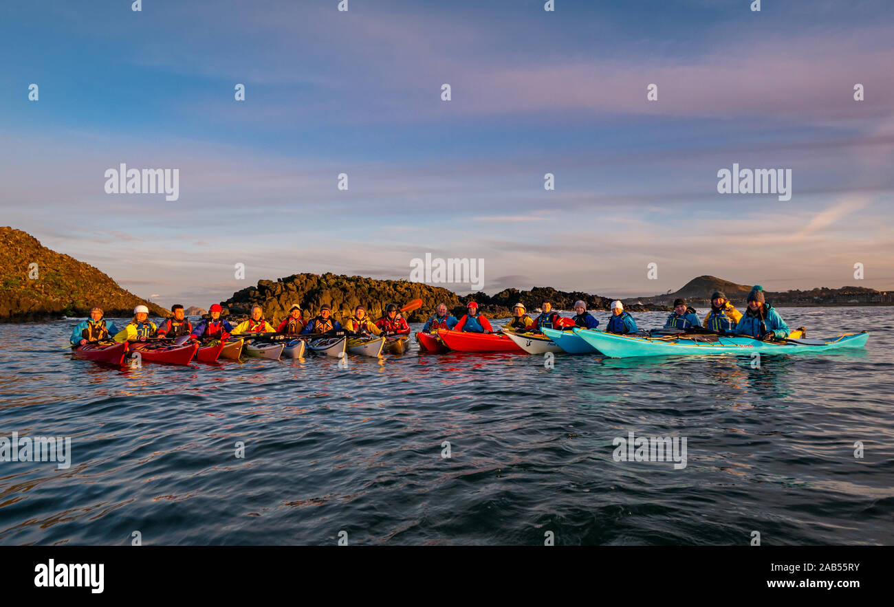 Los miembros del Club de Kayak de Mar de Lothian posan para una fotografía de grupo, en la isla de cordero al atardecer, Firth of Forth, Escocia, Reino Unido Foto de stock