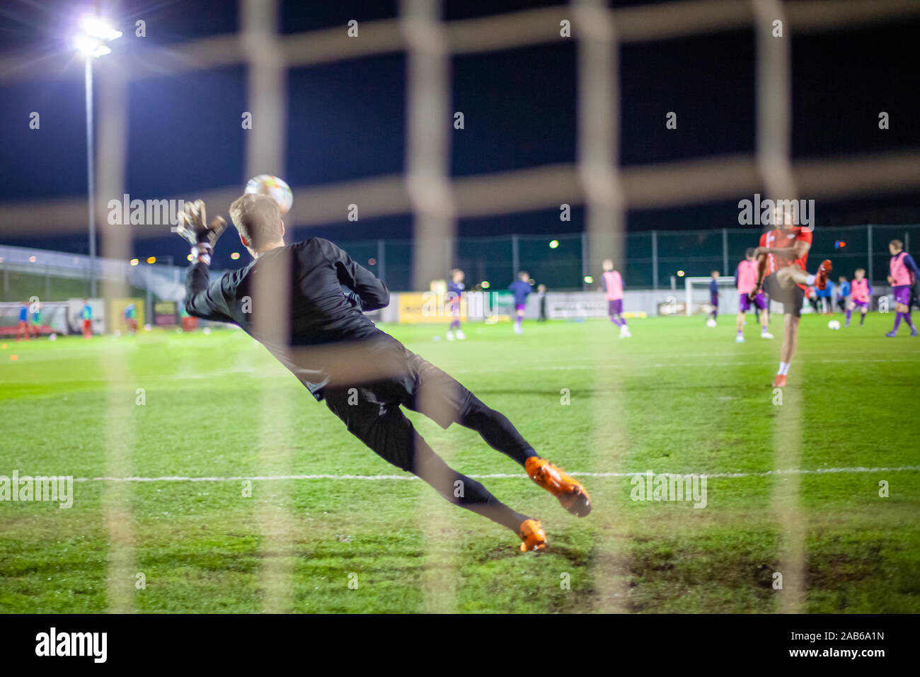 El portero atrapa la pelota cuando la defensiva de gol durante un partido de fútbol Foto de stock