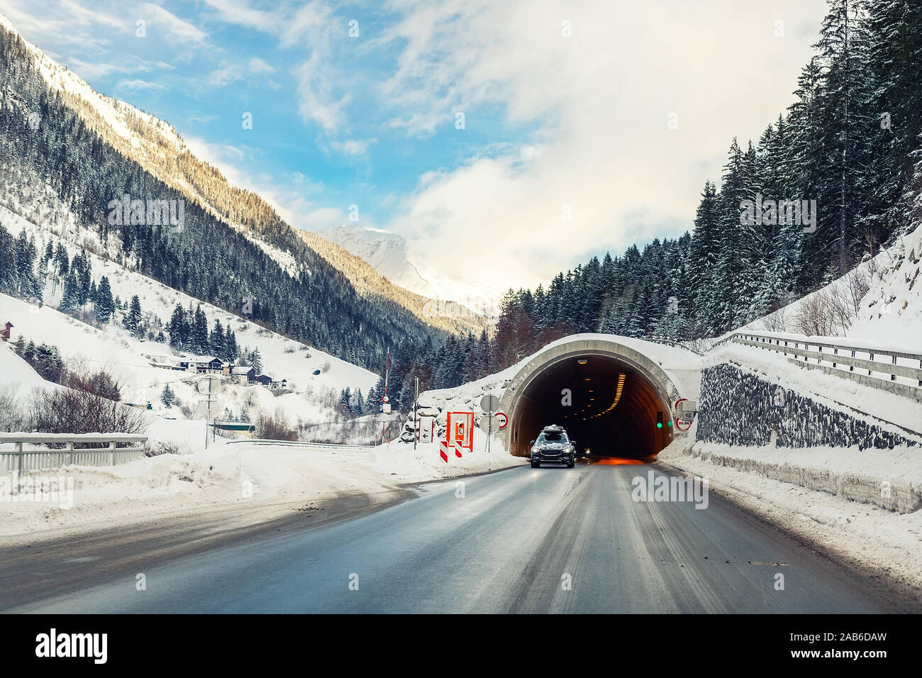 En invierno el paisaje con túnel de carretera alpina, bosque, montañas y cielo azul sobre fondo en frío brillante día soleado. Viaje en coche viaje viajar en familia. Foto de stock