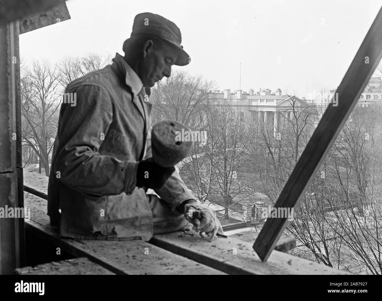 Trabajador de la construcción con maceta trabajando en el trabajo de la piedra en el anexo del Tesoro de EE.UU., con vistas de la Casa Blanca en el fondo. Washington, D.C., ca. 1916-1918 Foto de stock