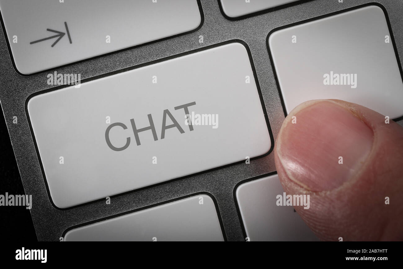 Un hombre presionando una tecla en un teclado de ordenador con la palabra chat, chat online imagen concepto Foto de stock