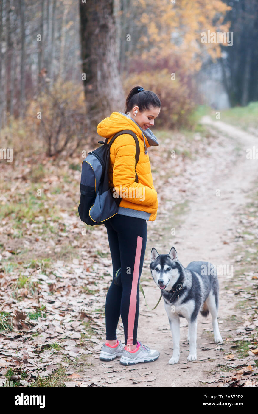 La mujer va con un perro a caminar en el parque en otoño Foto de stock