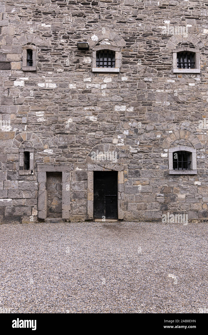 Muro de piedra gris con puerta y ventanas que dan a un patio interior en la Cárcel de Kilmainham, Dublín, Irlanda Foto de stock
