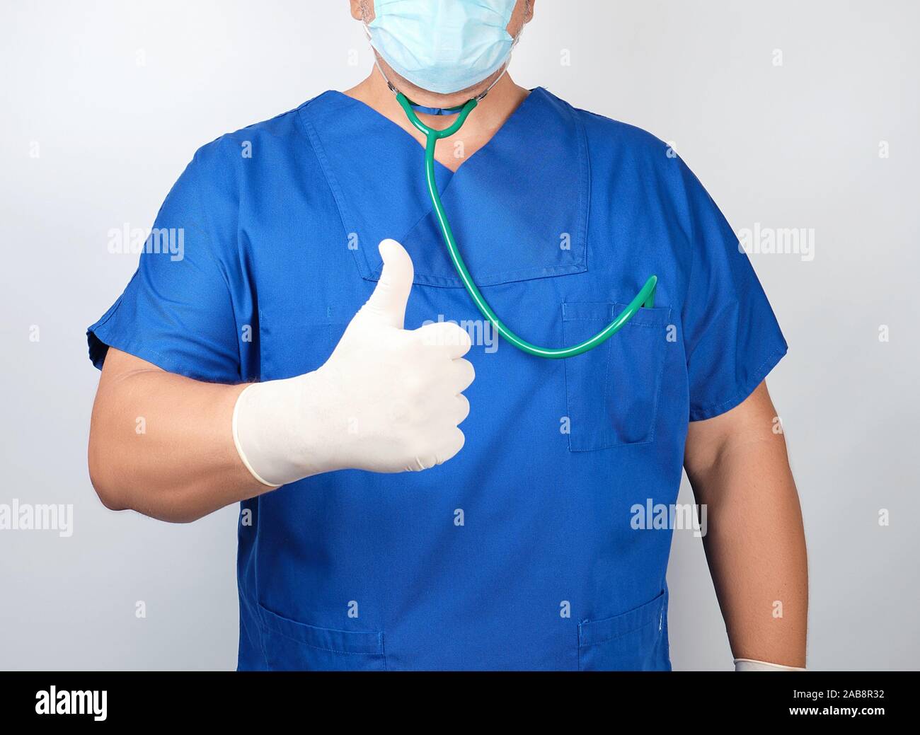 medico-varon-en-uniforme-azul-y-guantes-blancos-de-latex-muestra-como-gesto-de-la-mano-derecha-con-el-pulgar-levantado-abr