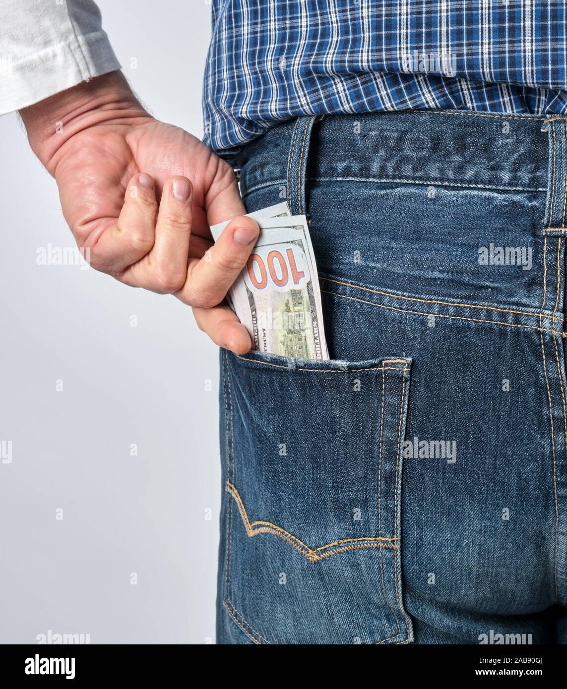 Brújula Deliberadamente pedestal Hombre en una camiseta y pantalones vaqueros azules plaid coloca papel de  dólares americanos en su bolsillo trasero, fondo blanco Fotografía de stock  - Alamy